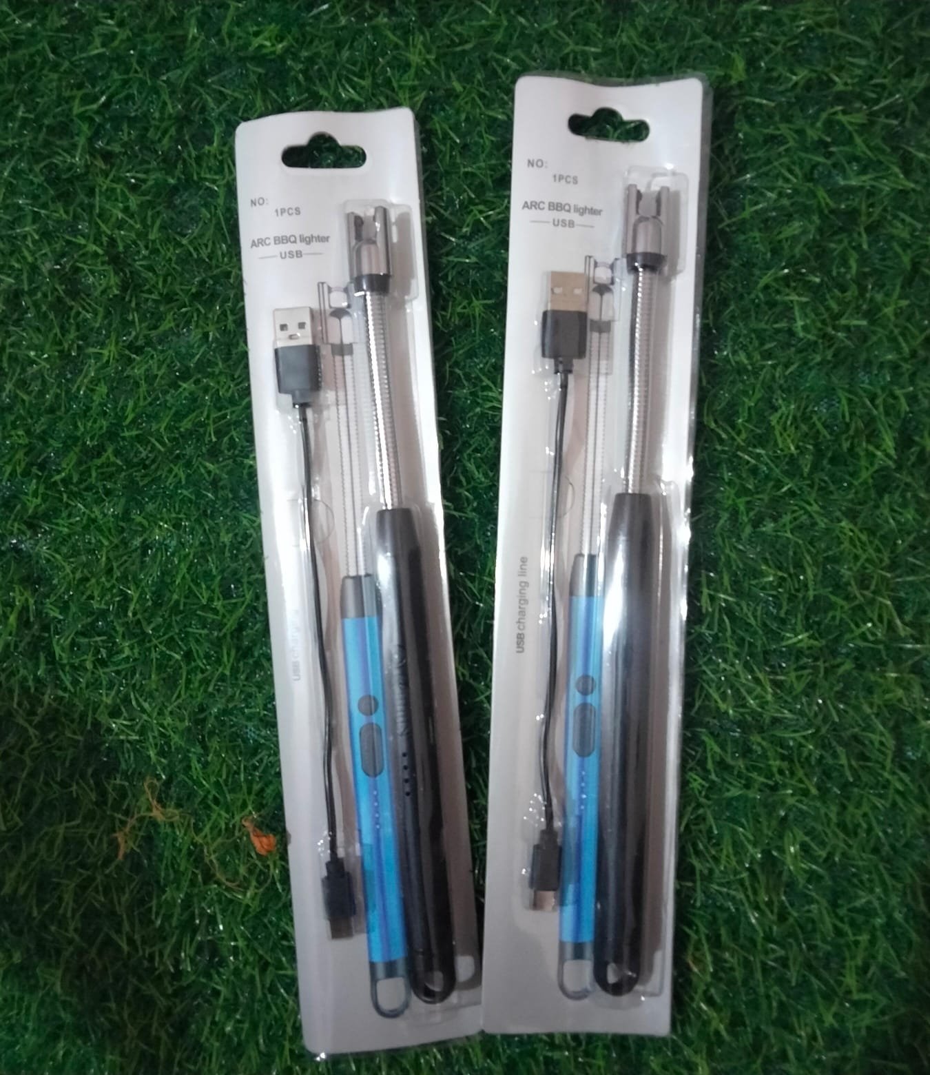 Two packs of ARC BBQ lighters with flexible necks and USB charging cables displayed in their retail blister packaging over a green grass surface