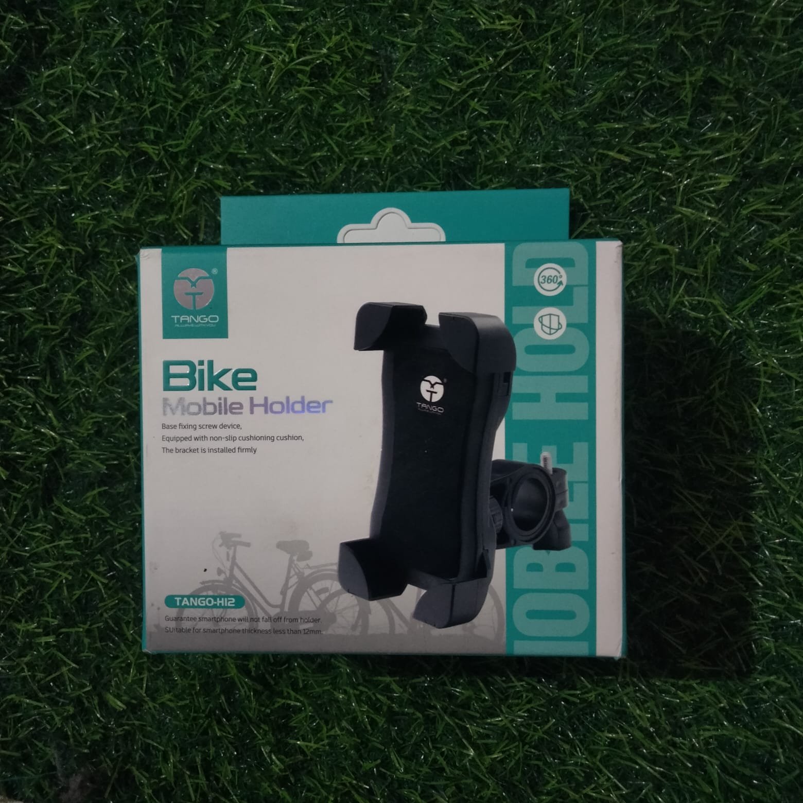TANGO Bike Mobile Holder retail packaging box displaying a black heavy-duty handlebar smartphone mount over a green grass backdrop