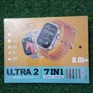 Ultra 2 7-in-1 smartwatch retail packaging box displaying a 2.01 inch big screen dial, an orange ocean strap, and icons for wireless charging and sports mode over a green grass backdrop