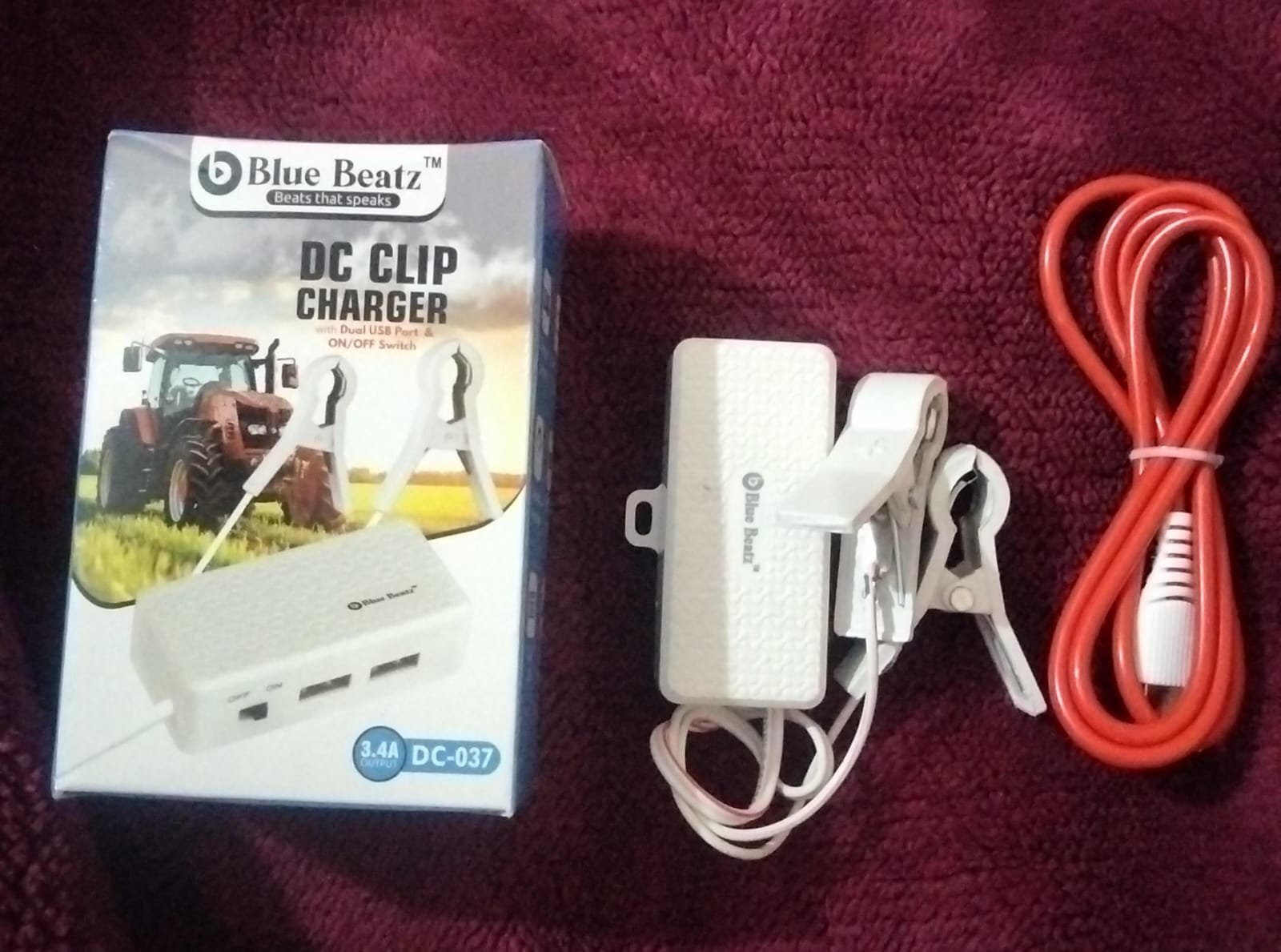 Blue Beatz DC-037 3.4A DC Clip Charger with its retail packaging box showing a tractor, featuring alligator clips and dual USB ports